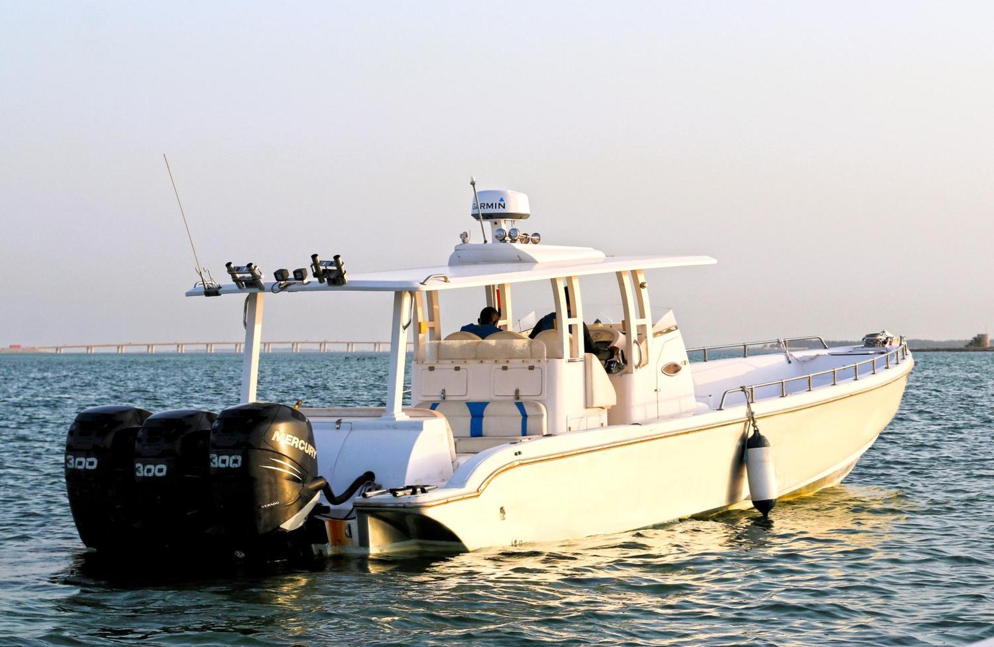 Lagoona Beach Luxury Resort And Spa Manama Dış mekan fotoğraf The photo shows a large, white motorboat equipped with three powerful outboard engines at the stern. The boat has a sleek design, with a spacious open deck and a covered cabin area that likely provides shelter and controls for navigation. The scene i