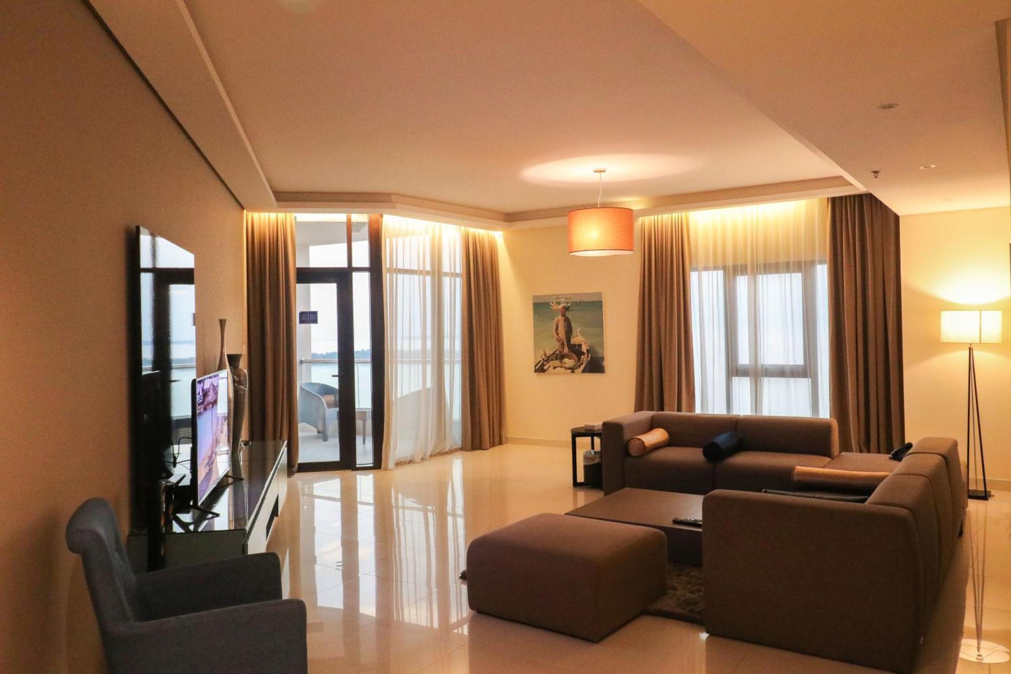 Lagoona Beach Luxury Resort And Spa Manama Dış mekan fotoğraf The photo shows a modern living room with a spacious and elegant design. It features a large couch in neutral tones, a soft ottoman, and a stylish coffee table. The walls are painted in a light color, and there are large windows with sheer curtains a